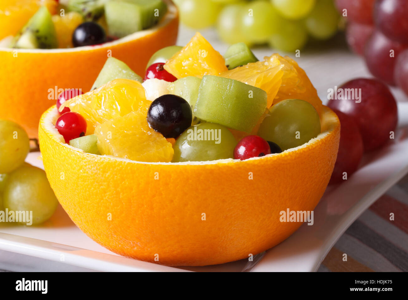 Hollowed-out oranges filled with fruit close-up on a plate. horizontal Stock Photo