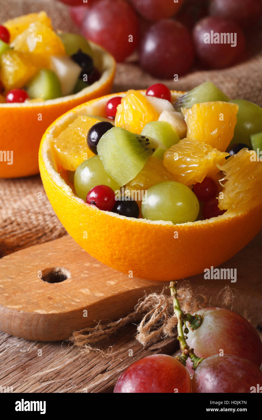Oranges stuffed with fresh fruit salad close-up on the table. Vertical Stock Photo
