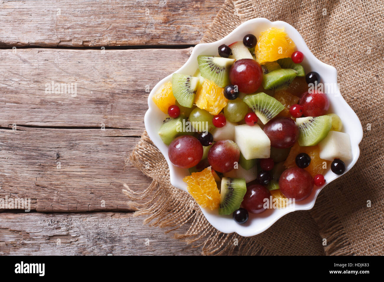 Fruit salad in white plate on the table. horizontal view from above, rustic style Stock Photo