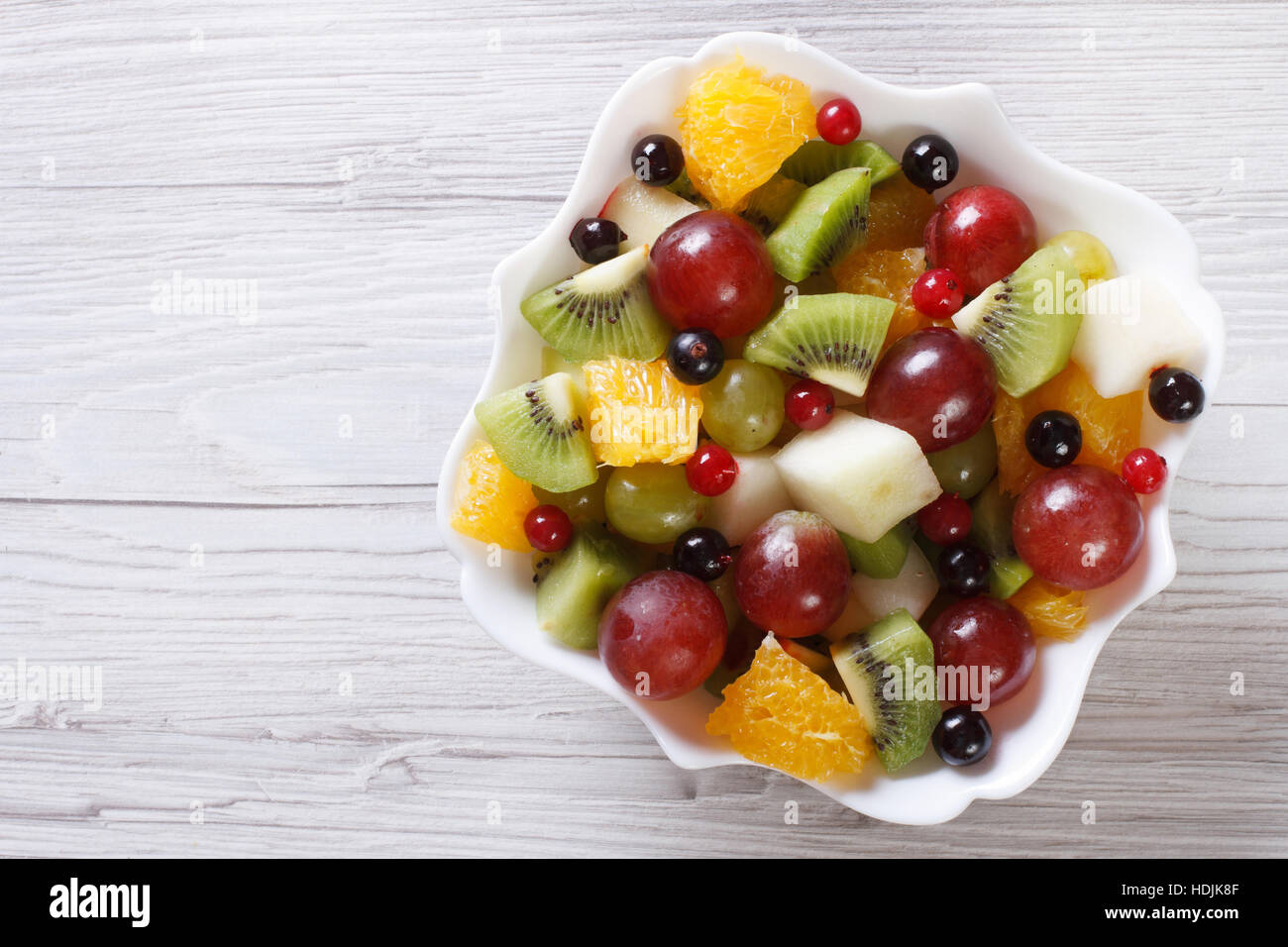 Fruit salad of oranges, grapes. pears, kiwi in white plate close up. horizontal view from above Stock Photo