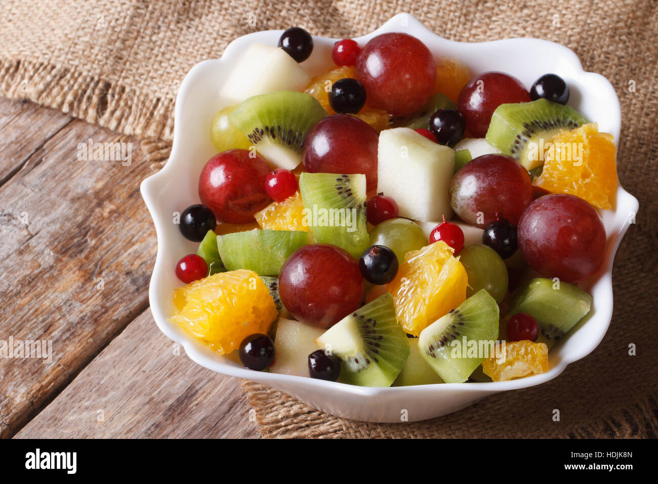 Fruit salad of oranges, grapes. pears, kiwis in a white bowl closeup. horizontal Stock Photo