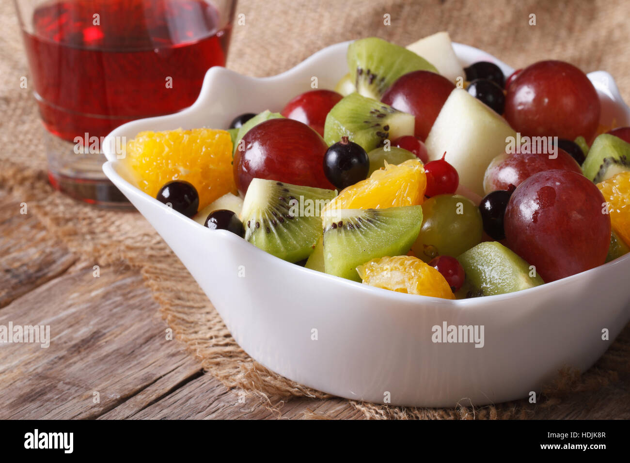 Fruit salad of oranges, grapes. pears, kiwis in a white bowl and grape juice closeup. horizontal Stock Photo