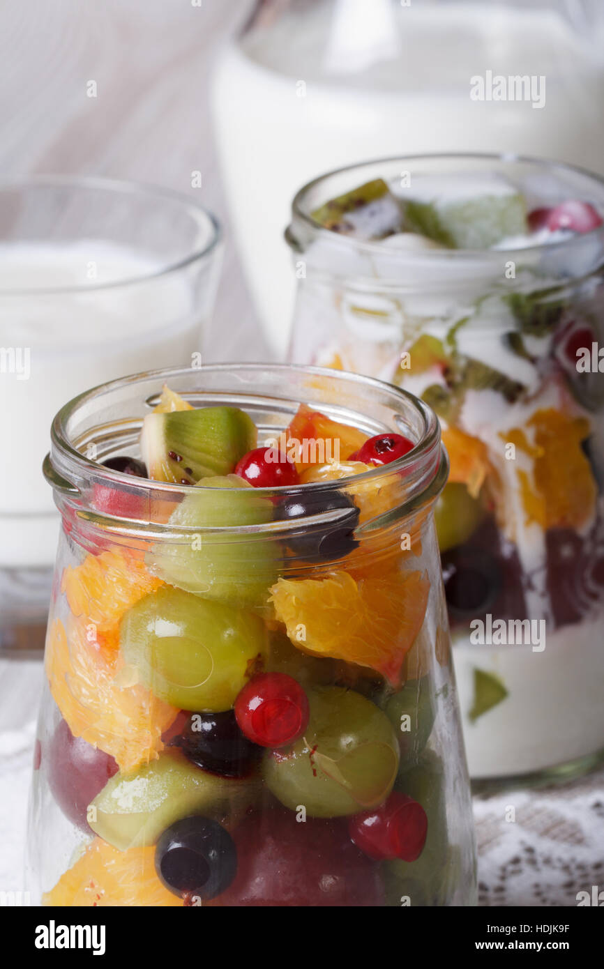 Healthy food: fresh fruit in a glass jar and yogurt on the table macro vertical Stock Photo
