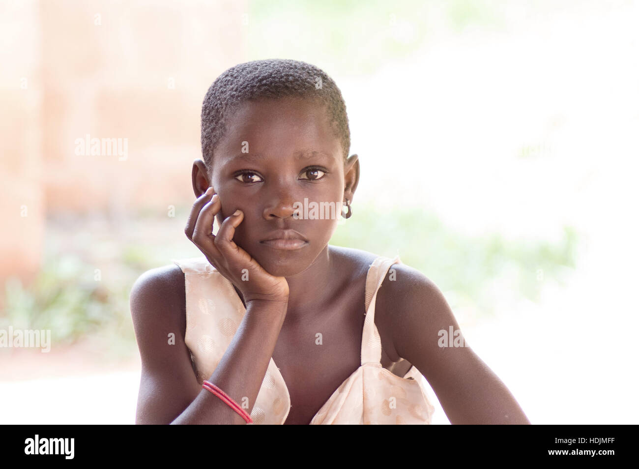 girl sitting gaze to the camera and hand under chin , seems to be hungry. Stock Photo