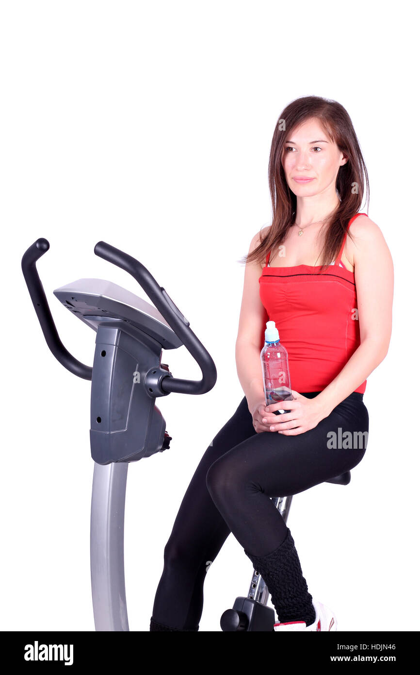 girl with bottle of water sitting on cross trainer Stock Photo