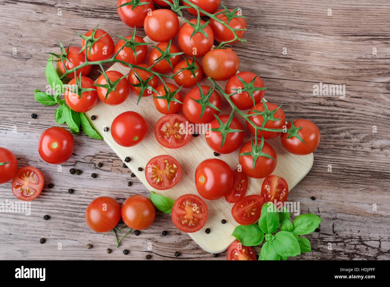 Scattered cherry tomatoes and pepper balls with leaves of basil on the ...