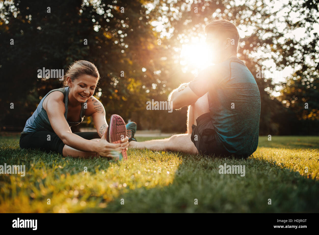 Caucasian couple doing their stretches in park. Fit young man and woman exercising in morning. Stock Photo