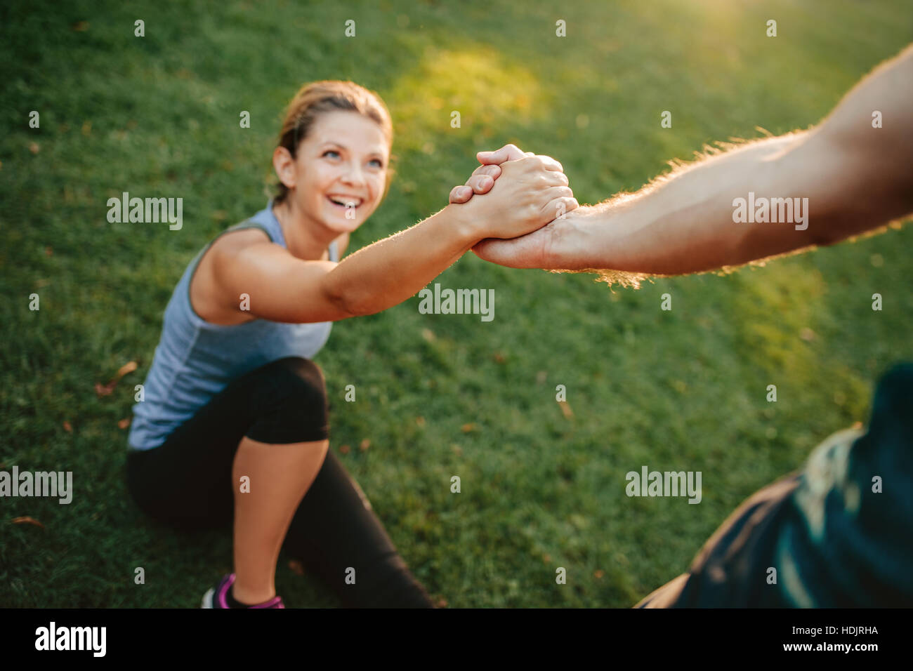 Man helping her girlfriend with focus on hands. Couple exercising in park. Stock Photo