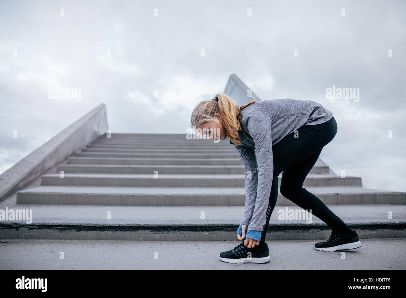 Side view shot of woman tying her shoelace, getting ready for outdoor workout. fitness female preparing for a run. Stock Photo