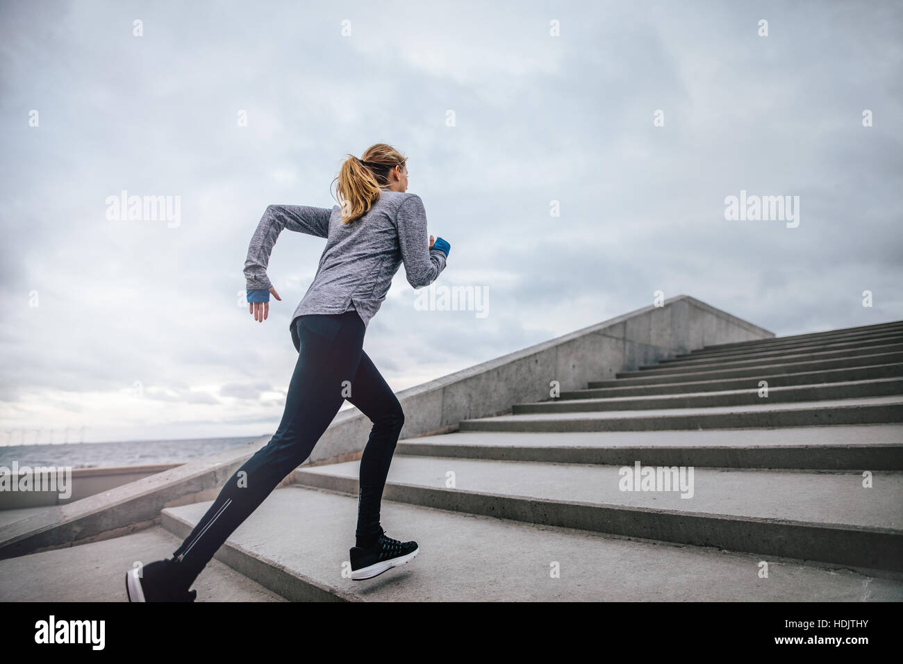 Outdoor shot of fit young woman running on steps. Runner exercising on stairs in morning. Stock Photo