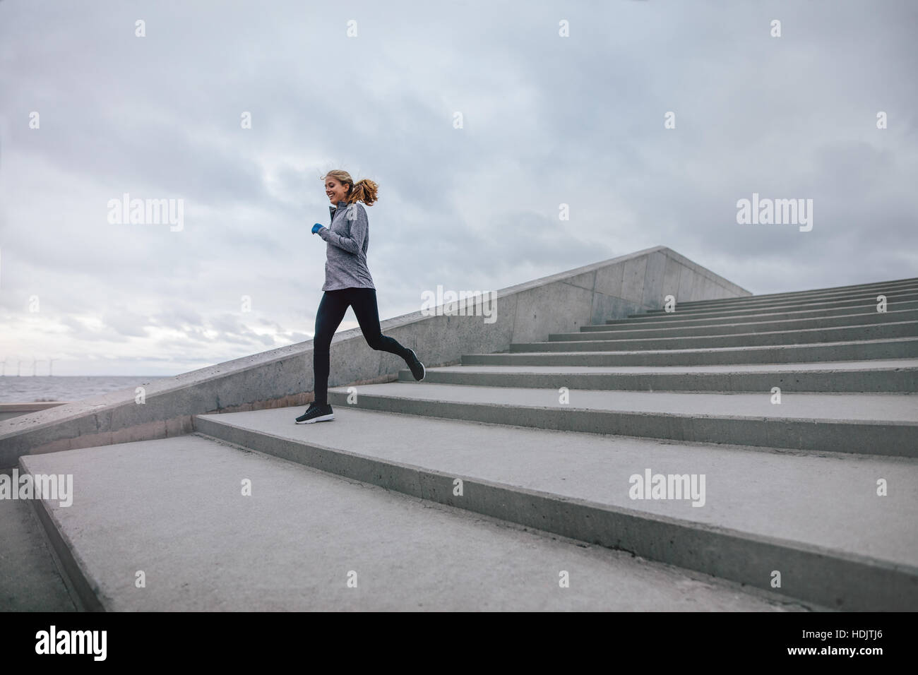 Outdoors shot of fitness woman running down on steps. Runner exercising on stairs in morning. Stock Photo