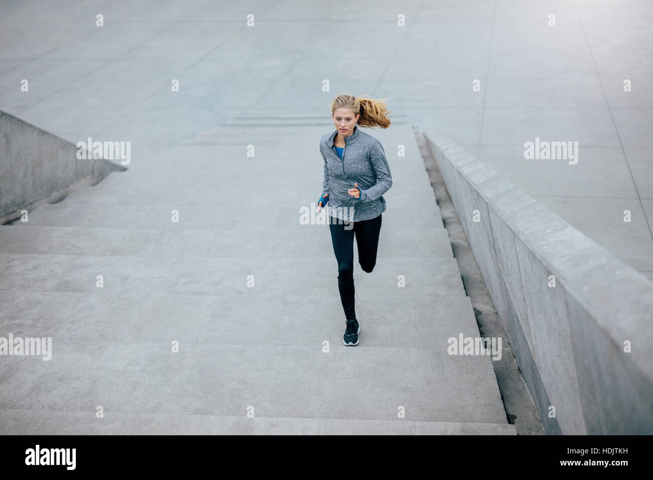 Shot of fitness female running up the steps in city. Healthy woman on morning run. Stock Photo