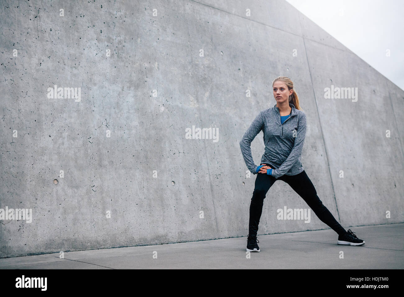 Full length shot of female stretching in morning. Young sports woman exercising outdoors. Stock Photo