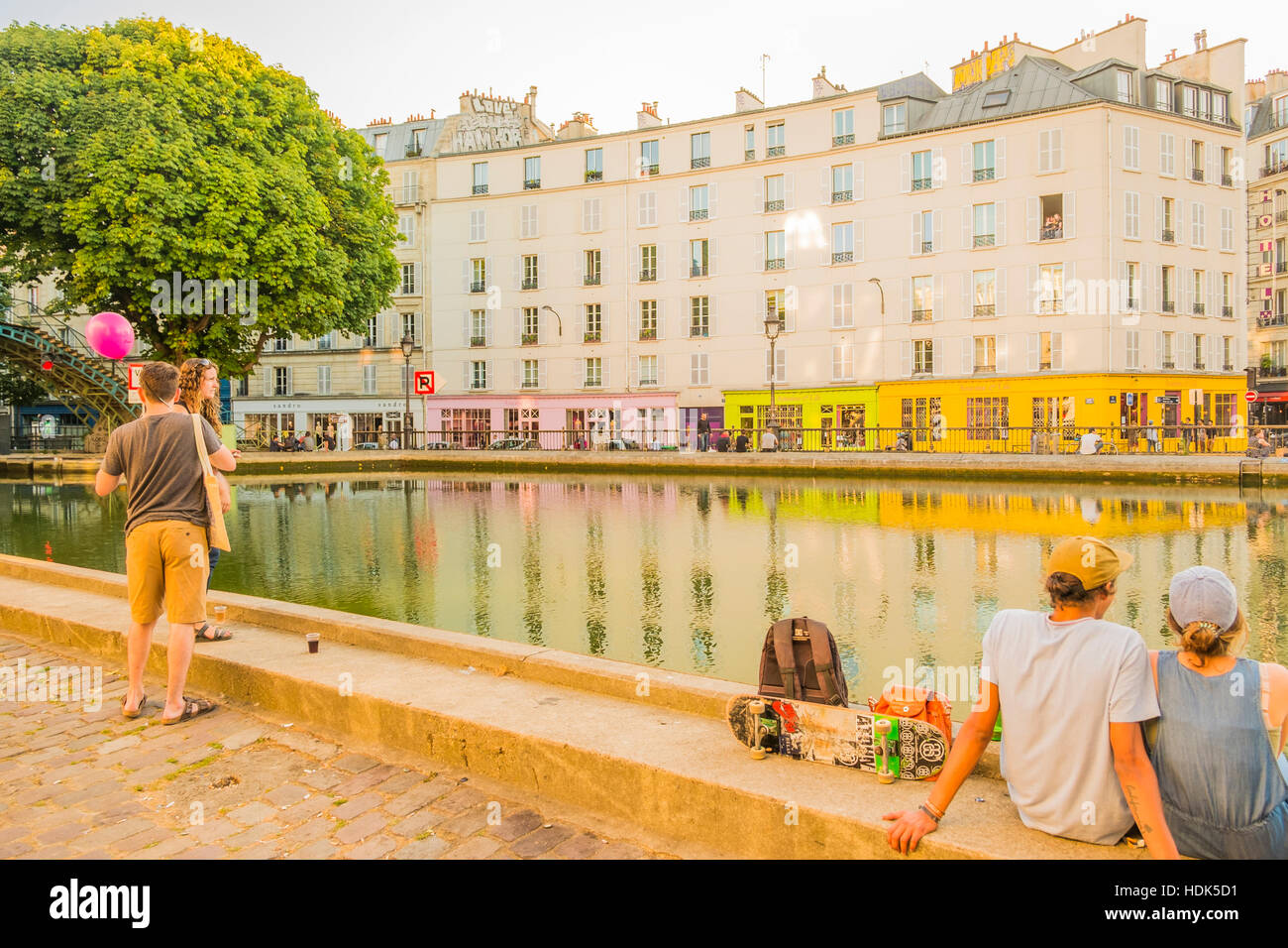 young people relaxing at canal saint martin at dusk, quai de jemmapes looking at quai de valmy Stock Photo