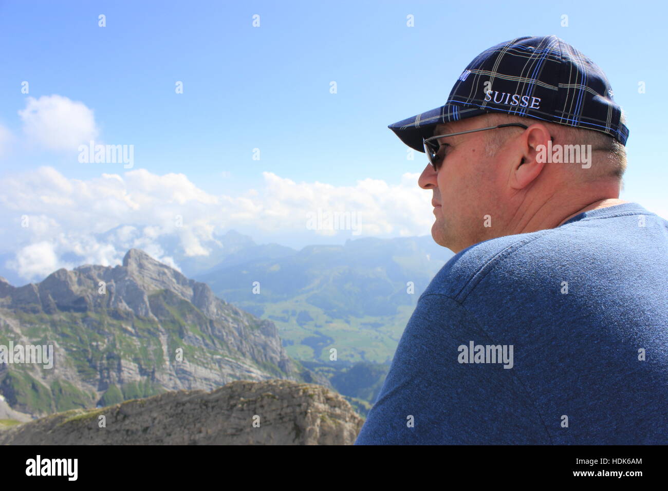 An American tourist enjoys the beautiful view from the peak of Switzerland's Säntis Mountain in the Swiss Alps. Stock Photo