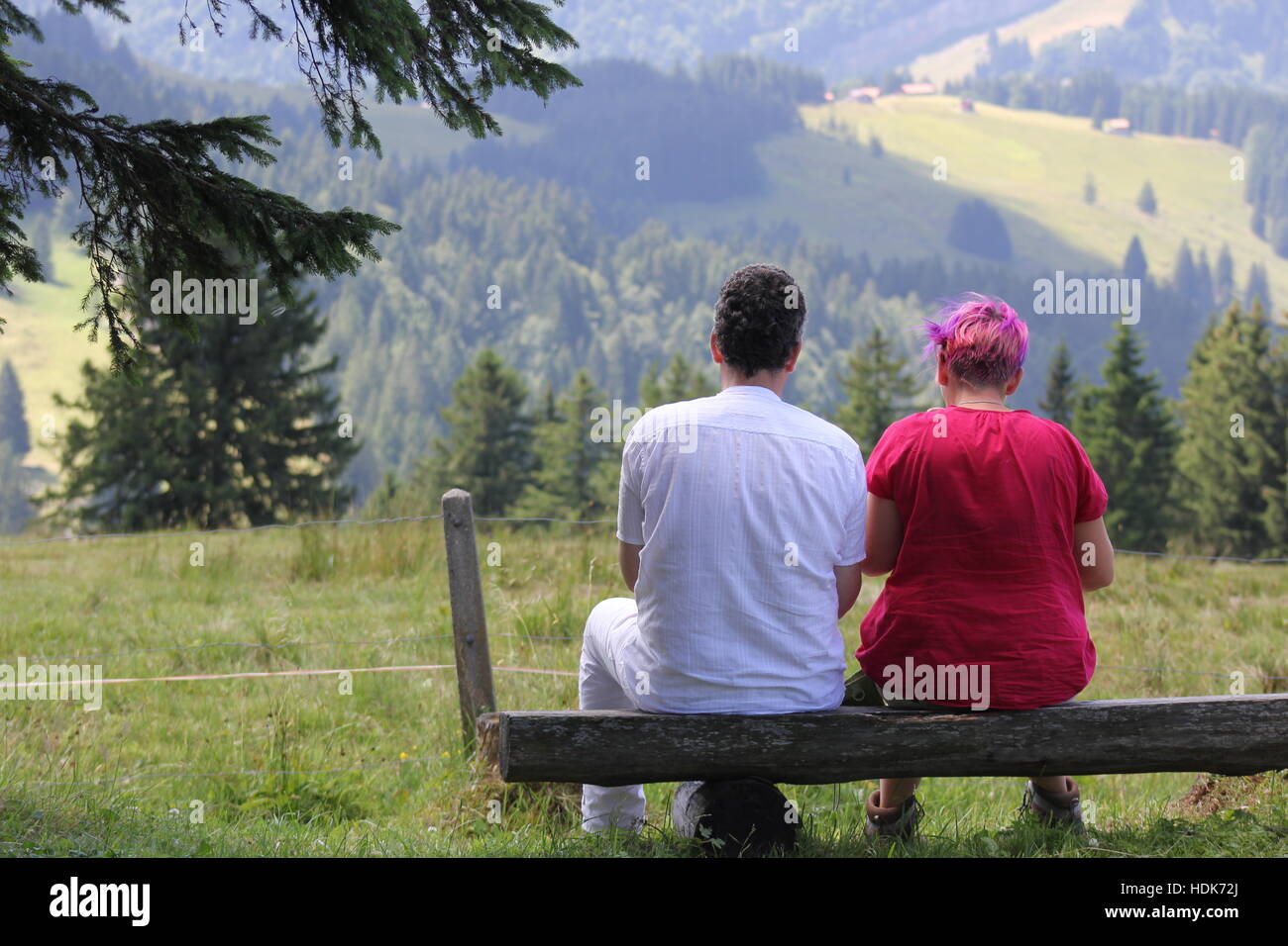 A colorful German couple enjoys a beautiful view of the valley near Switzerland's Säntis Mountain in the Swiss Alps. Stock Photo