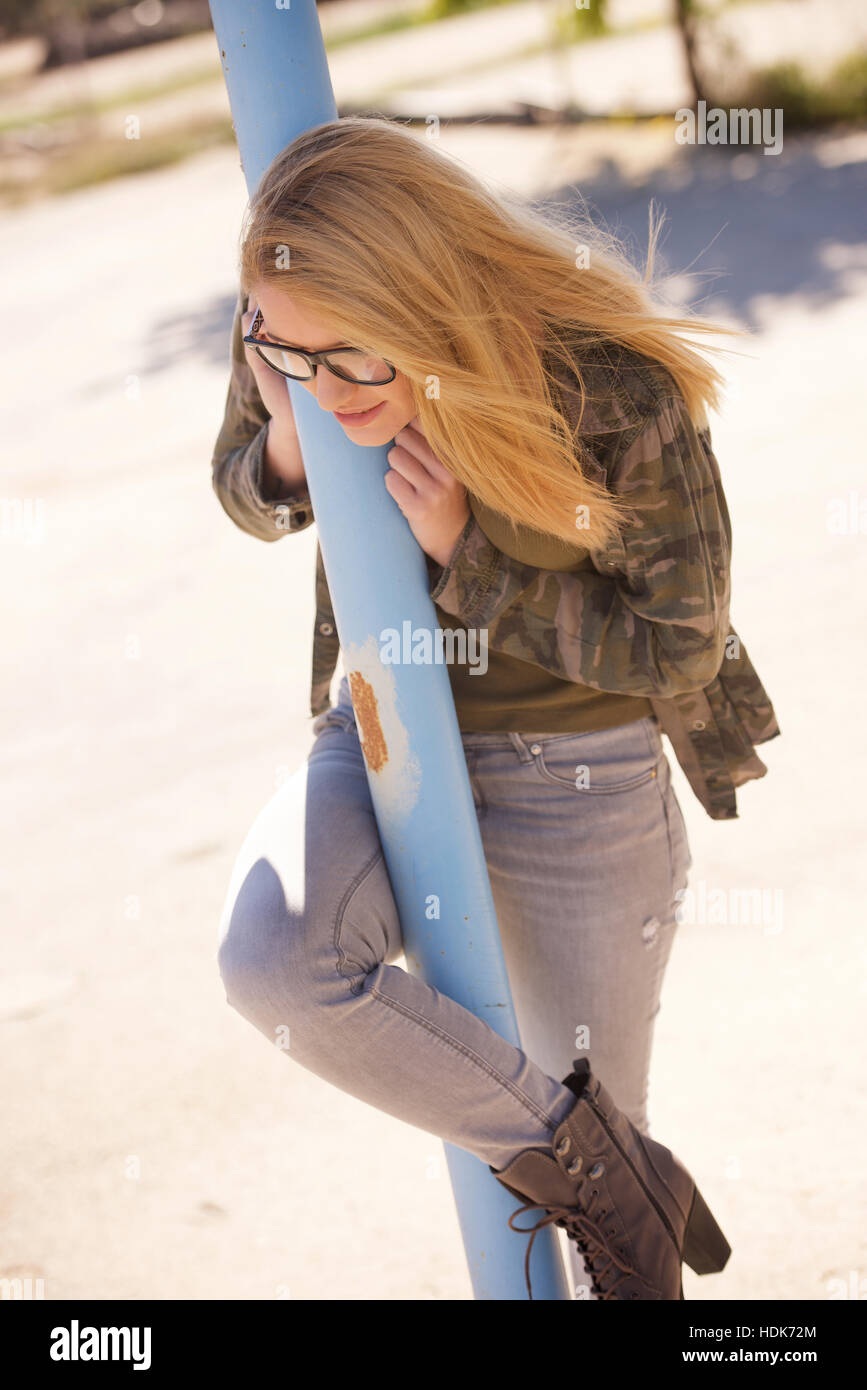 Blonde teenage girl outdoors with glasses, jeans and green top. Stock Photo