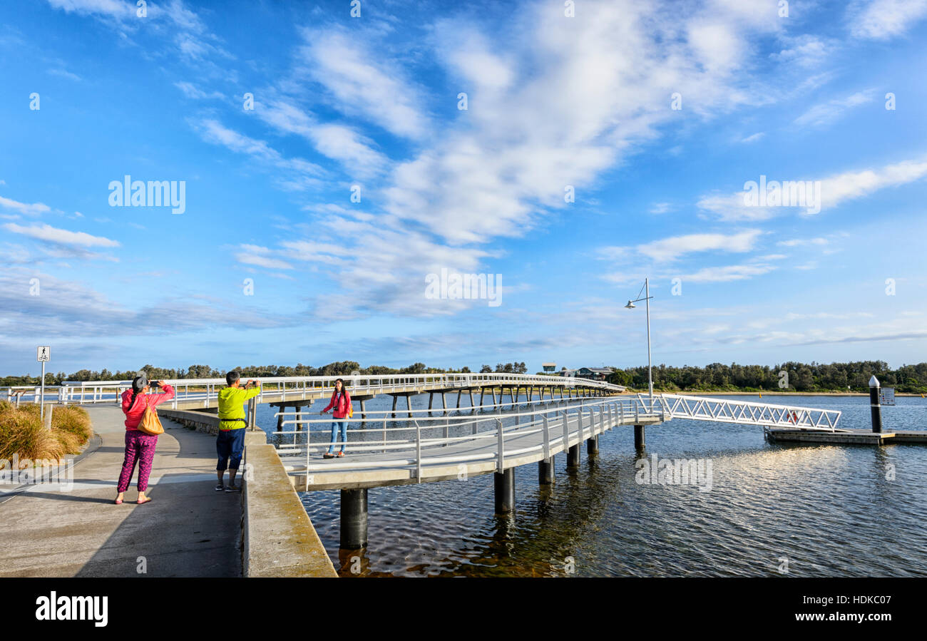 Asian tourists wearing bright colours taking pictures at Cunninghame Arm Bridge, Lakes Entrance, Victoria, VIC, Australia Stock Photo