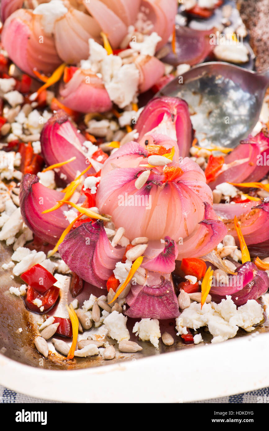 Red onion baked with goat cheese and pumpkin seeds. Vegetarian food in close up. Stock Photo