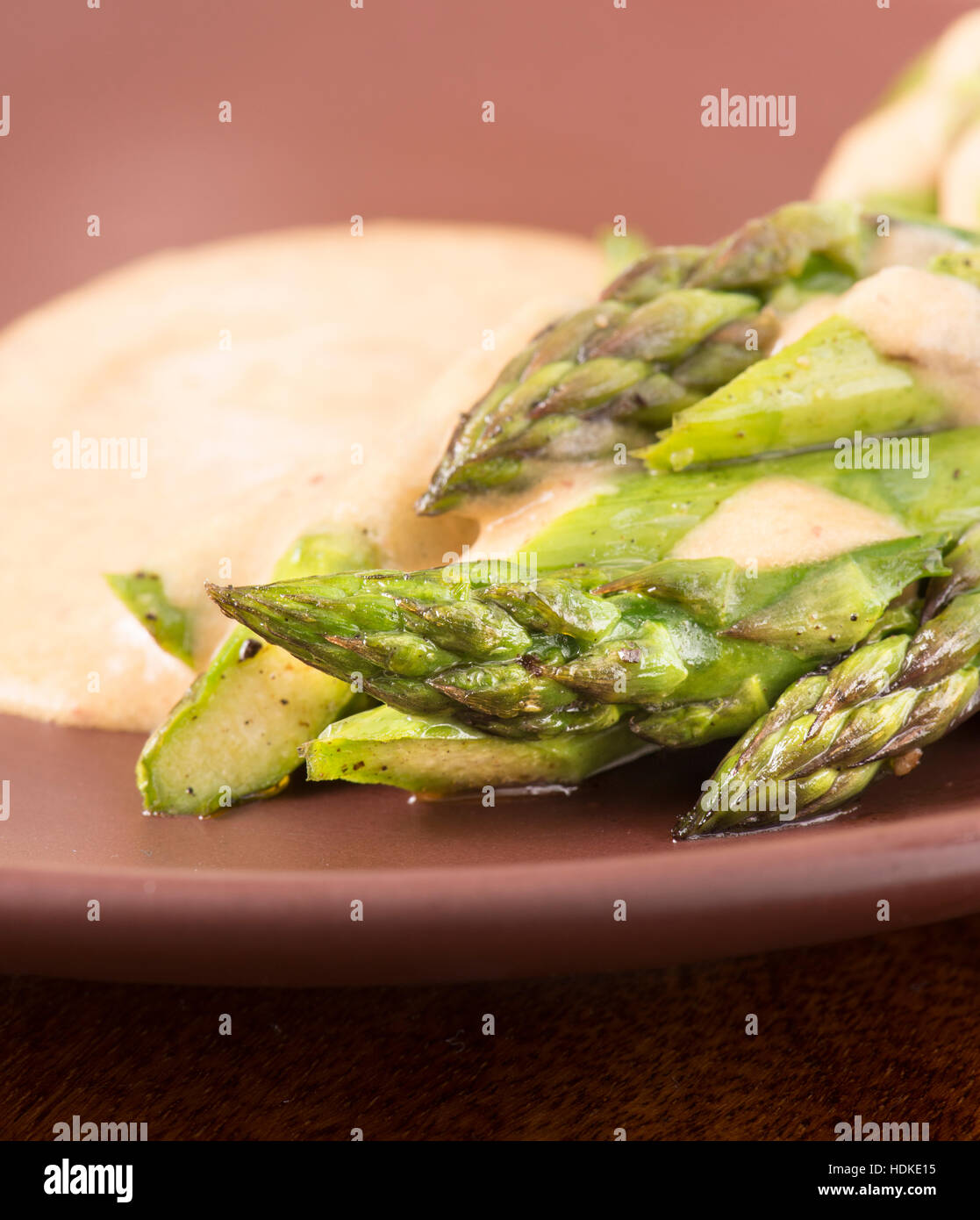 Fried green asparagus and sauce on plate in close up. Stock Photo
