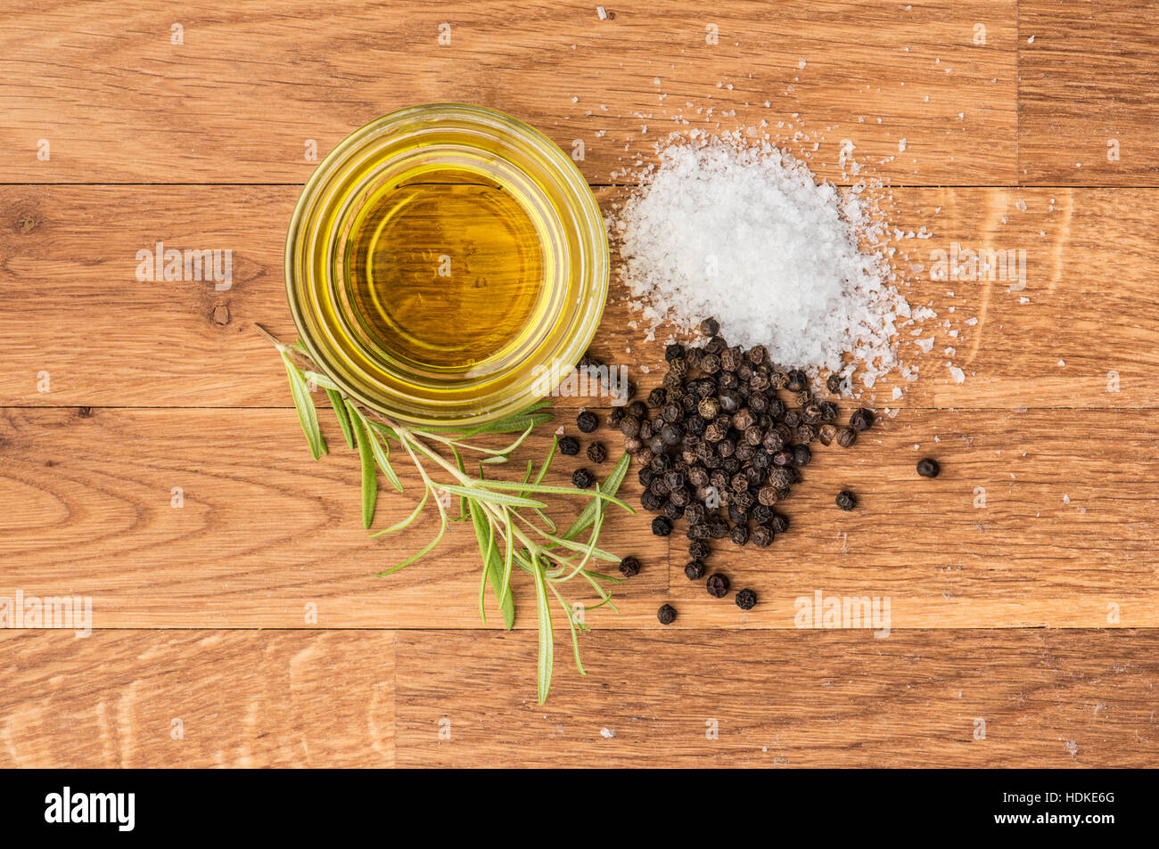 Salt, black pepper, olive oil and fresh rosemary on a wooden table. Food background with copy space. Stock Photo