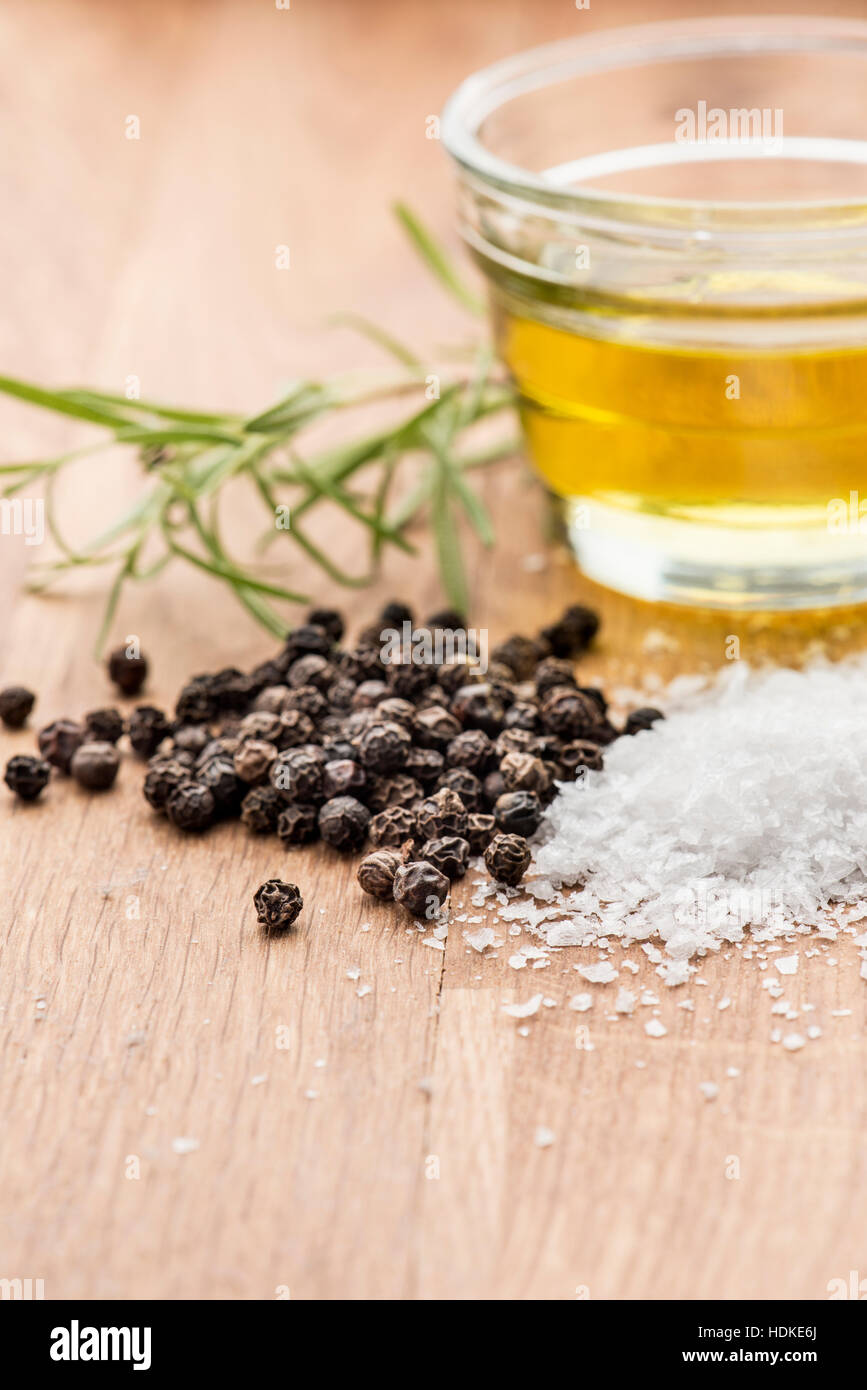 Salt, black pepper, olive oil and fresh rosemary on a wooden table. Food background with copy space. Stock Photo