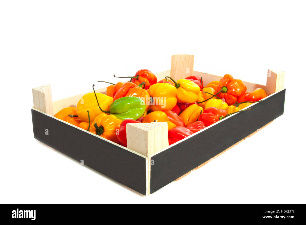 Hot colorful chili peppers in a wooden crate over white Stock Photo - Alamy