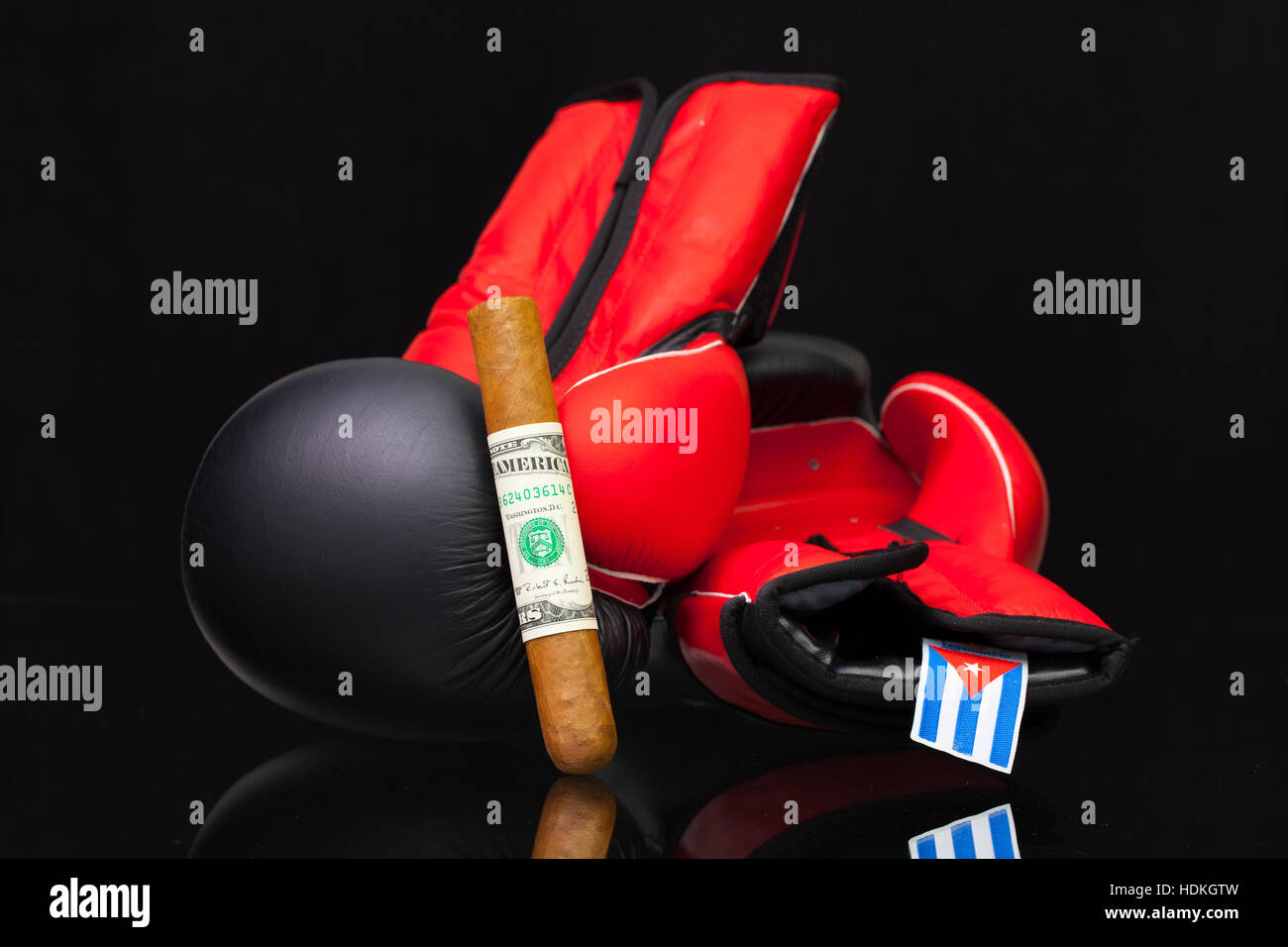 Red and black boxing gloves and luxury Cuban cigars on black glass