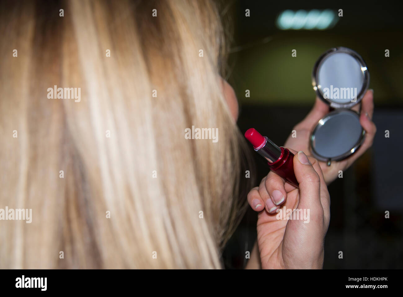 young woman paints her lips and looking to the small mirror Stock Photo