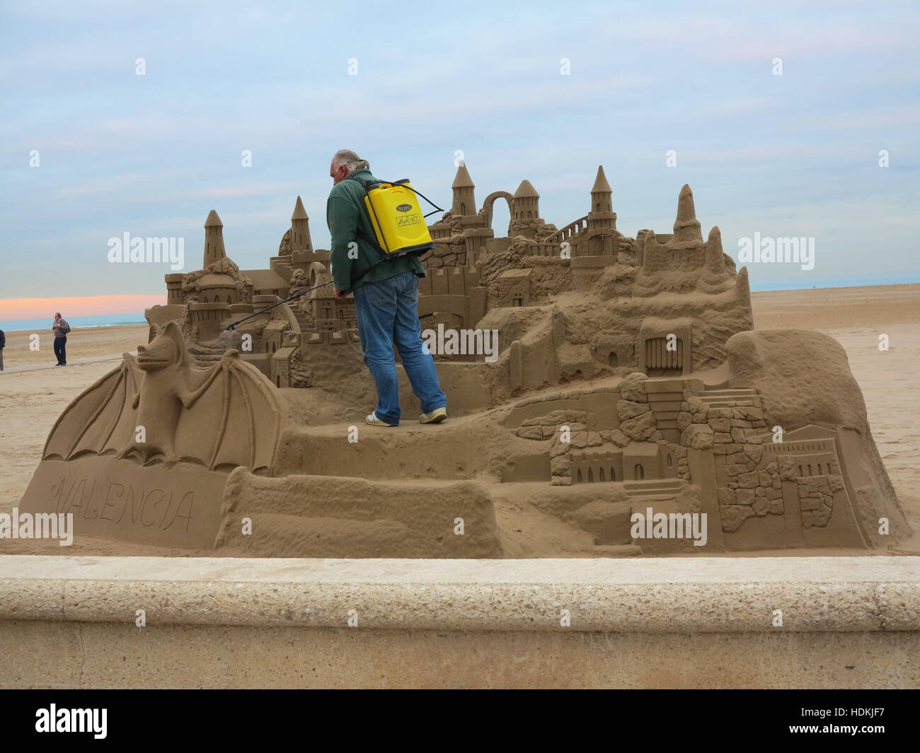 Man damping down a fantasy sand sculpture on the beach at Valencia, Spain Stock Photo