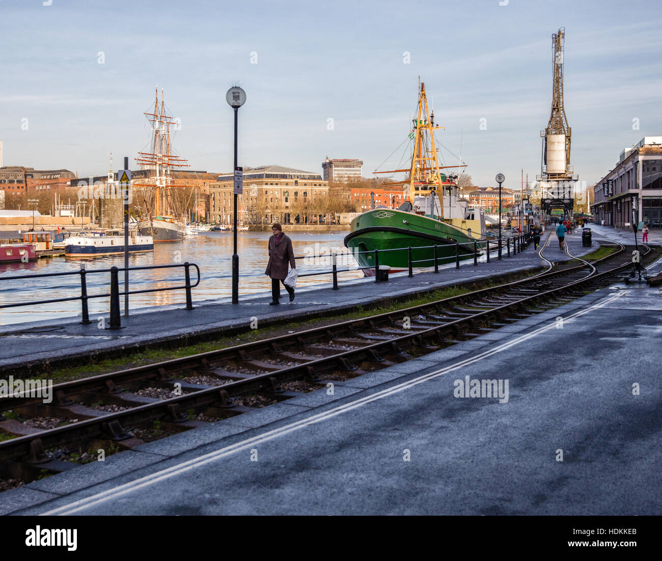 A man walking by Bristol floating harbour on a winter morning alongside the railway the cranes and M shed museum Stock Photo
