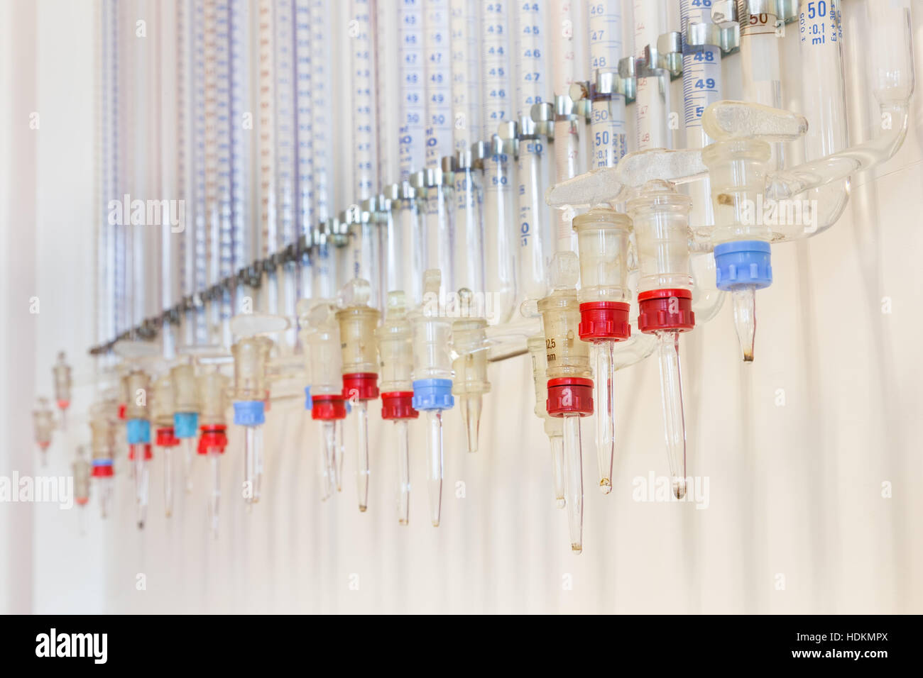 Glass burettes hanging at chemistry wall in high school Stock Photo