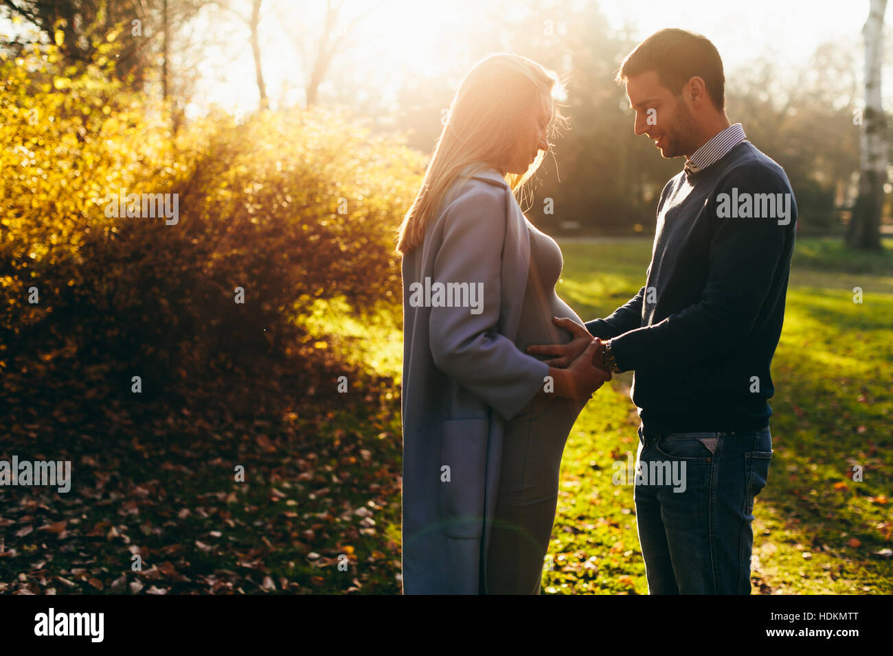 Pregnant woman and man posing at autumn park Stock Photo - Alamy