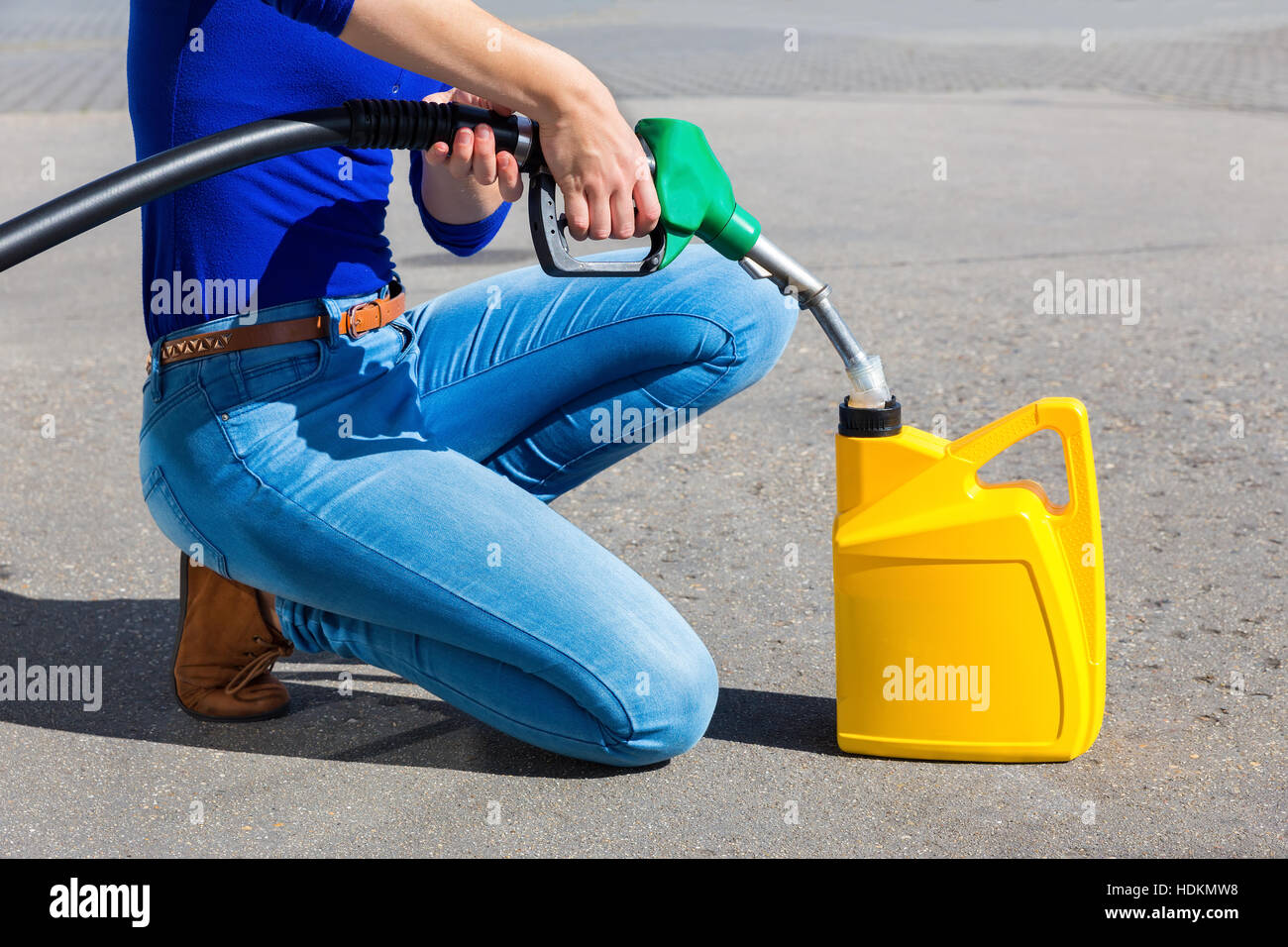 Woman filling yellow can with gasoline hose outdoors Stock Photo
