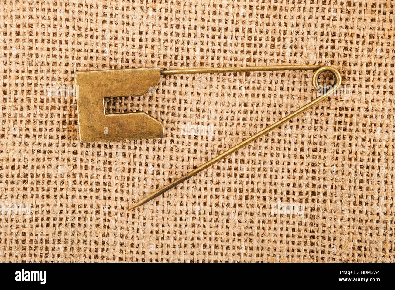 Vintage brooch or safety pin on jute background, Stock Photo