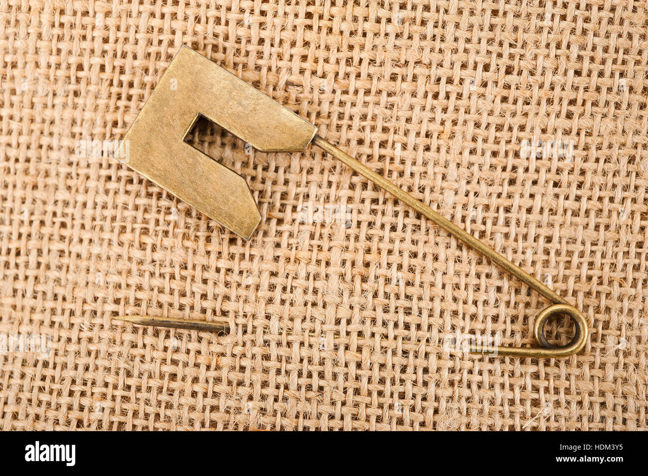 Vintage brooch or safety pin on jute background, Stock Photo