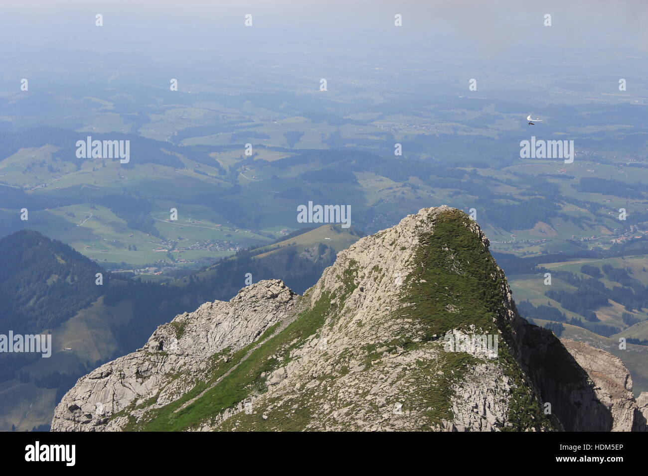 A hang glider passes over a peak near Switzerland's Säntis Mountain in the Swiss Alps. Stock Photo