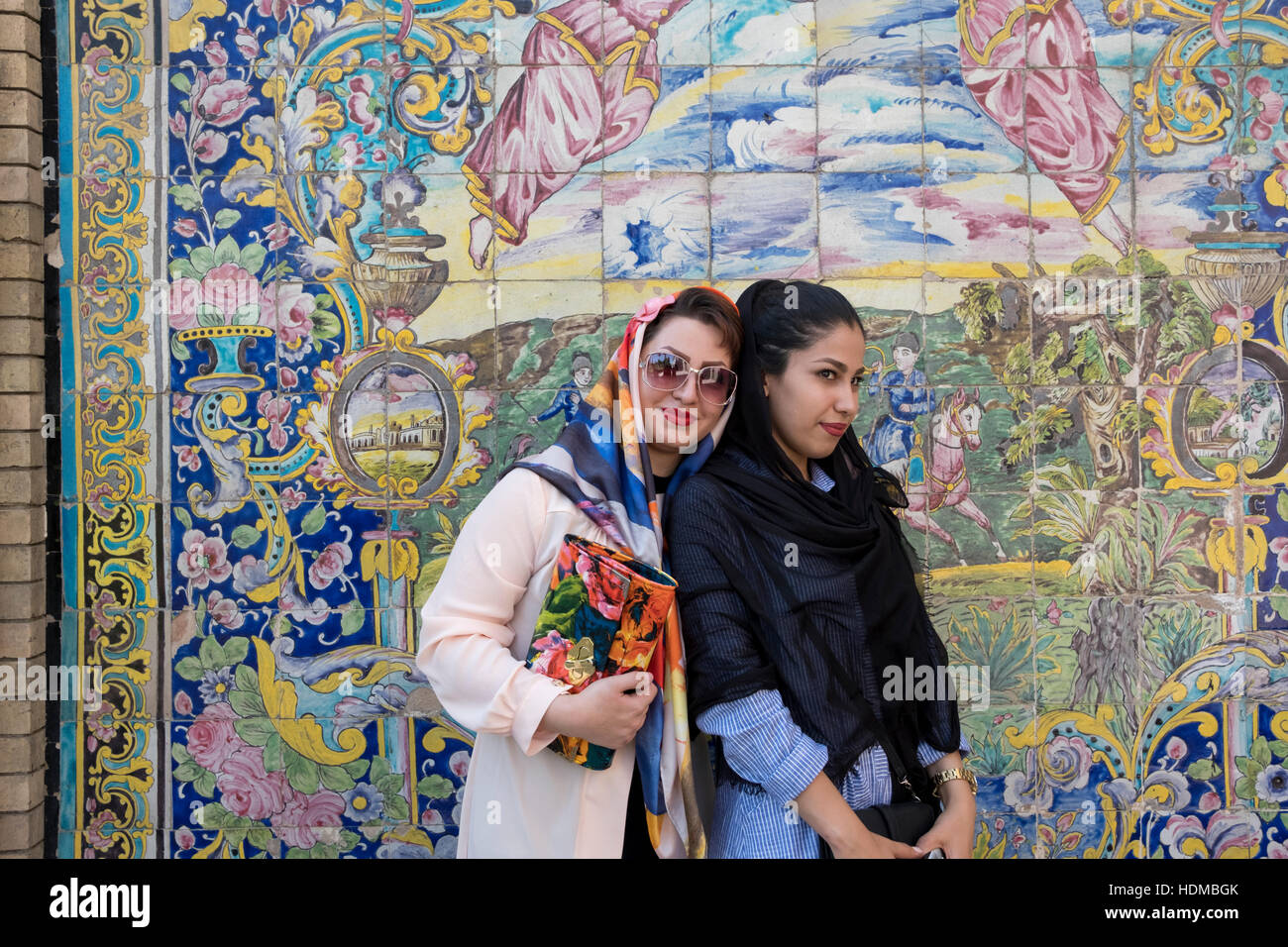 Tourists pose in front of colored mosaic tiles on a wall at the Golestan Palace, Panzdah Hordad Square, Tehran, Iran Stock Photo