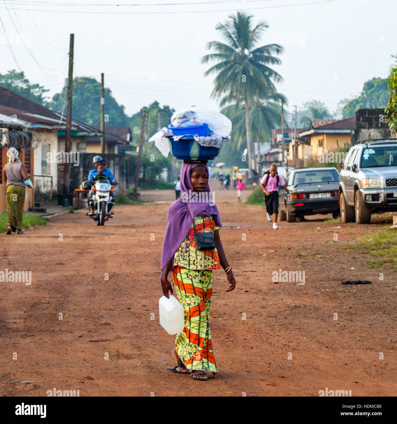 Woman in street of Kenema, Sierra Leone, carrying a big basket on her head Stock Photo