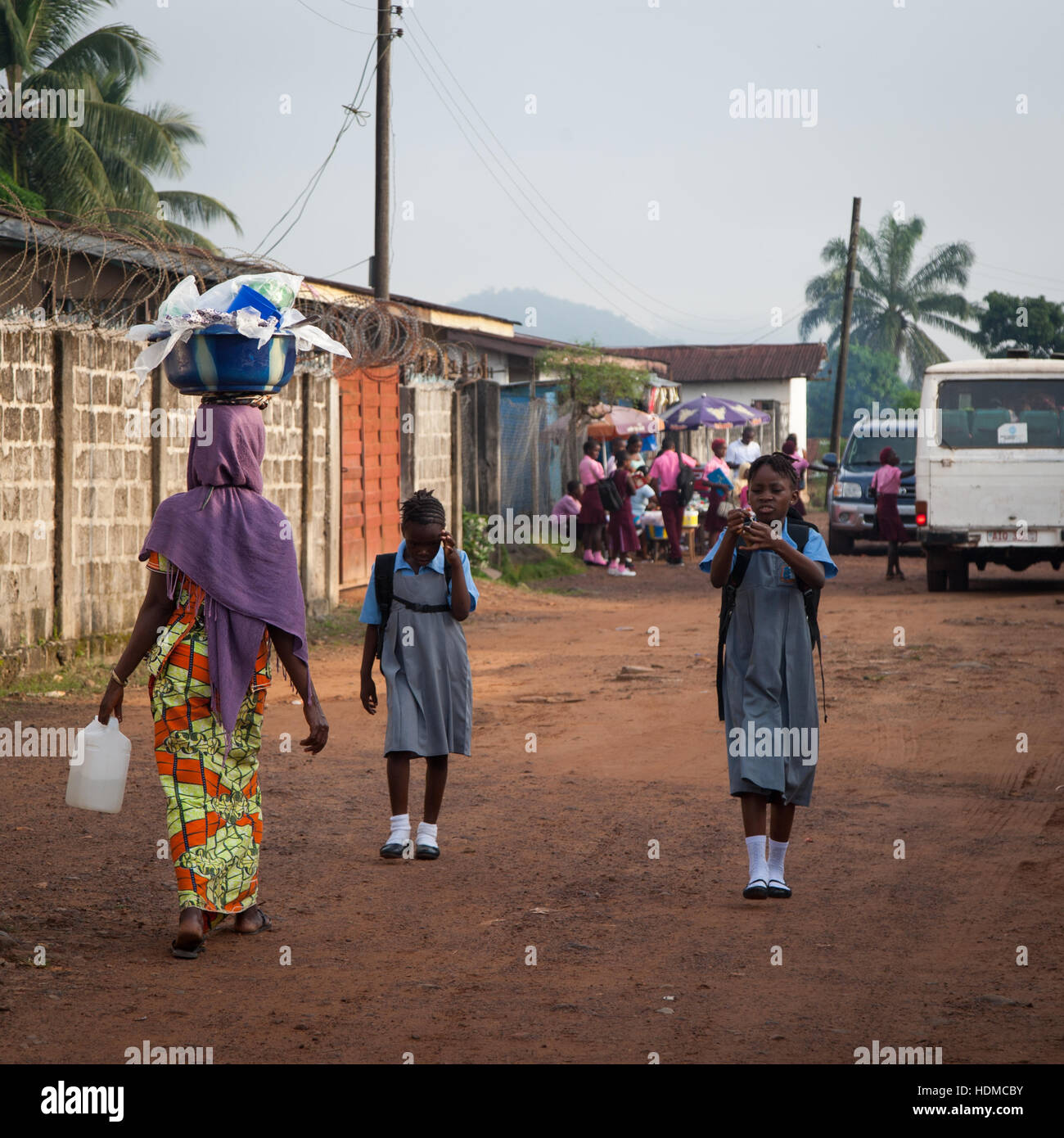 Woman and students in school uniform in the street of Kenema, Sierra Leone Stock Photo
