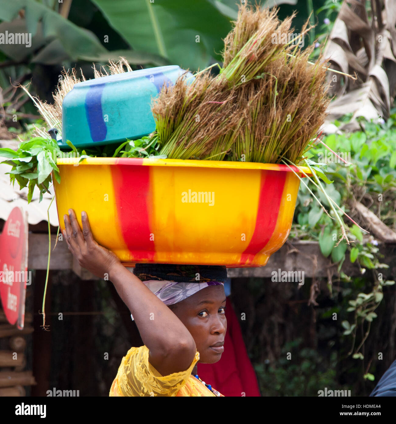 Eye contact in Sierra Leone. African woman carrying vegetables on her head Stock Photo