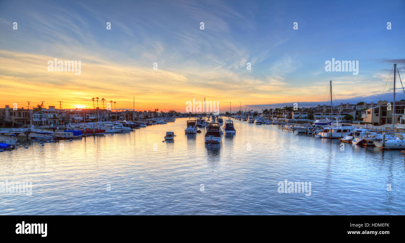 Balboa Island harbor at sunset with ships and sailboats visible from the bridge that leads into Balboa Island, Southern Californ Stock Photo