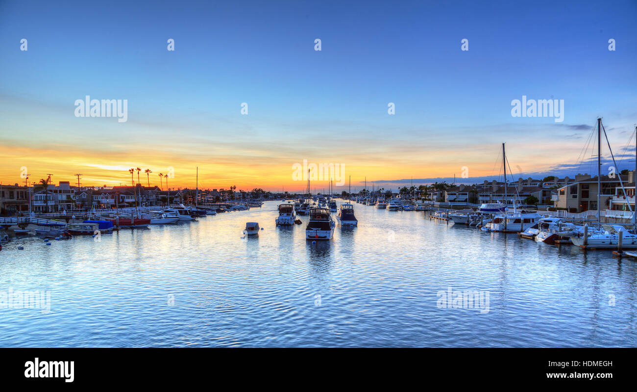 Balboa Island harbor at sunset with ships and sailboats visible from the bridge that leads into Balboa Island, Southern Californ Stock Photo