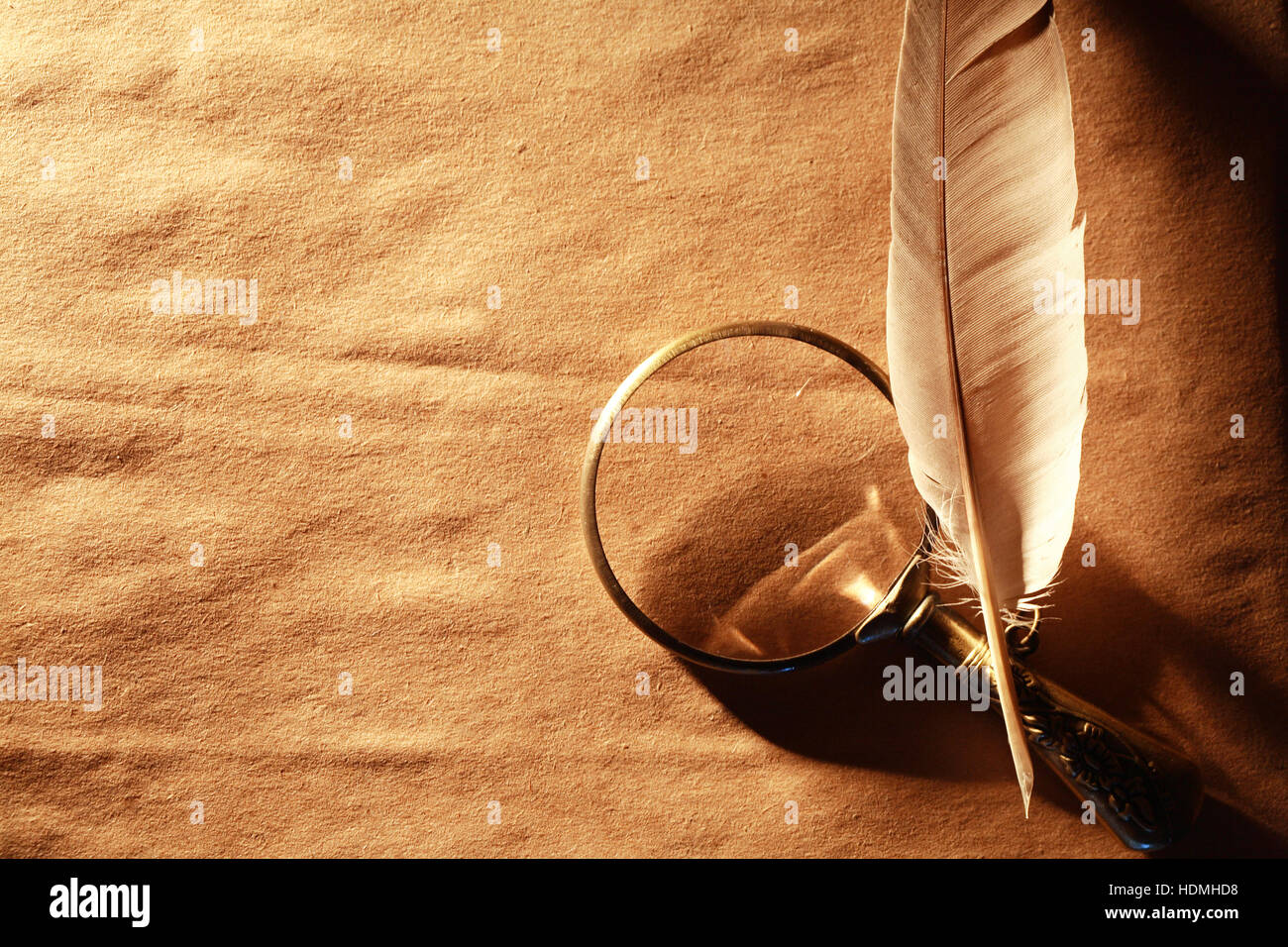 Art concept. Vintage magnifying glass near feather on nice old paper background Stock Photo