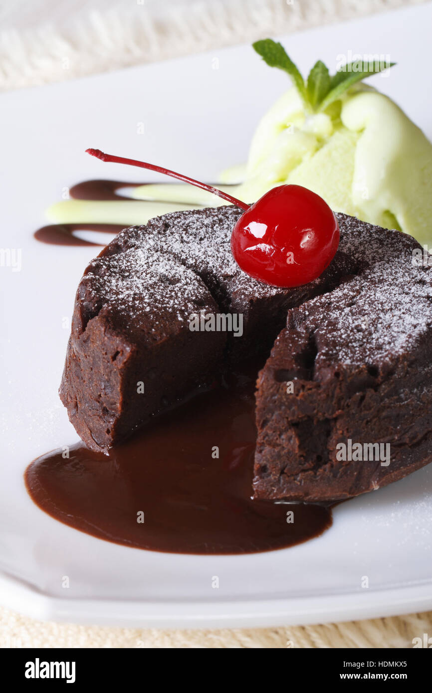 chocolate fondant cake with cherries and mint ice cream on a plate close-up. vertical Stock Photo