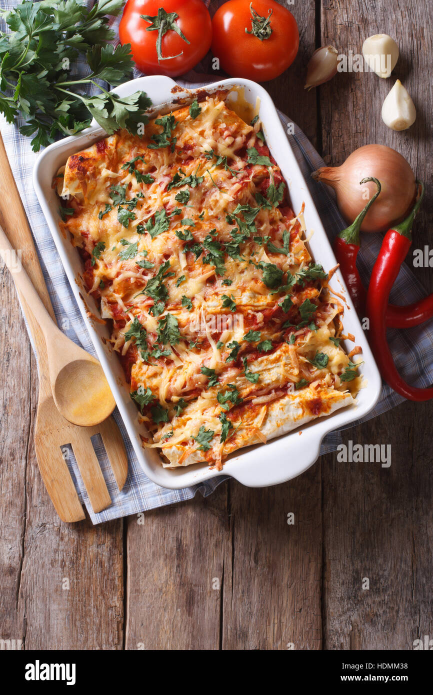 Mexican enchilada in a baking dish with the ingredients on the table. vertical view from above Stock Photo