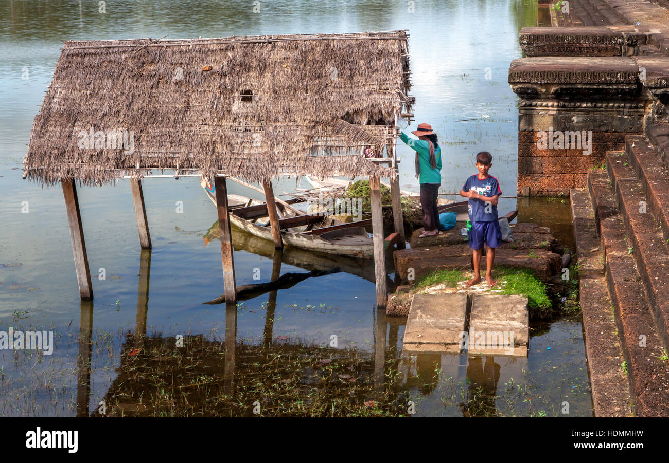 Khmer Cambodian boy and his mother fish and collect pond weeds in the moat in front of Angkor Wat, Kingdom of Cambodia. Stock Photo