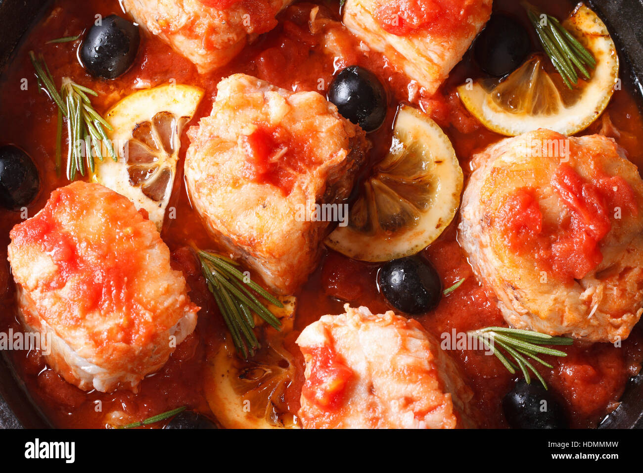 Fish fillet in tomato sauce with lemon and olives macro. horizontal