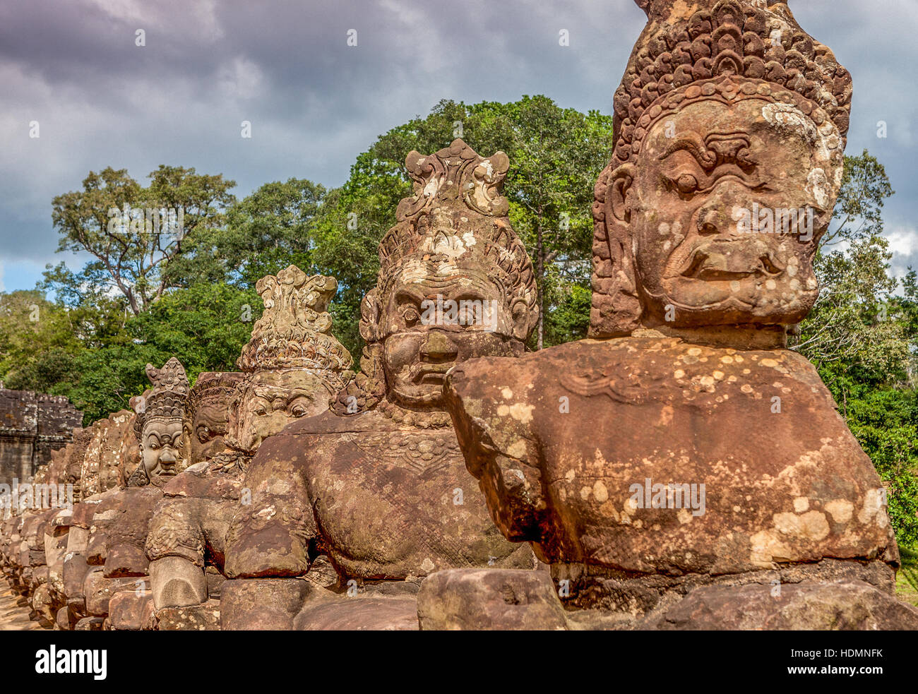 Asura statues hold the Cobra snake deity Naga on the side of the road leading to the South Gate of Ta Prohm, Cambodia. Stock Photo