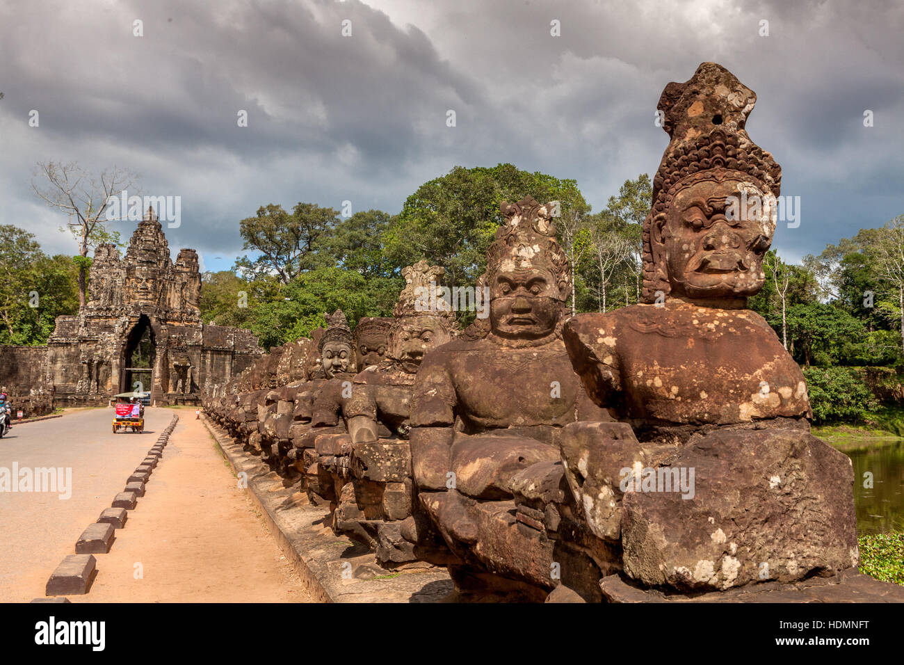 Asura statues hold the Cobra snake deity Naga on the side of the road leading to the South Gate of Ta Prohm, Cambodia. Stock Photo